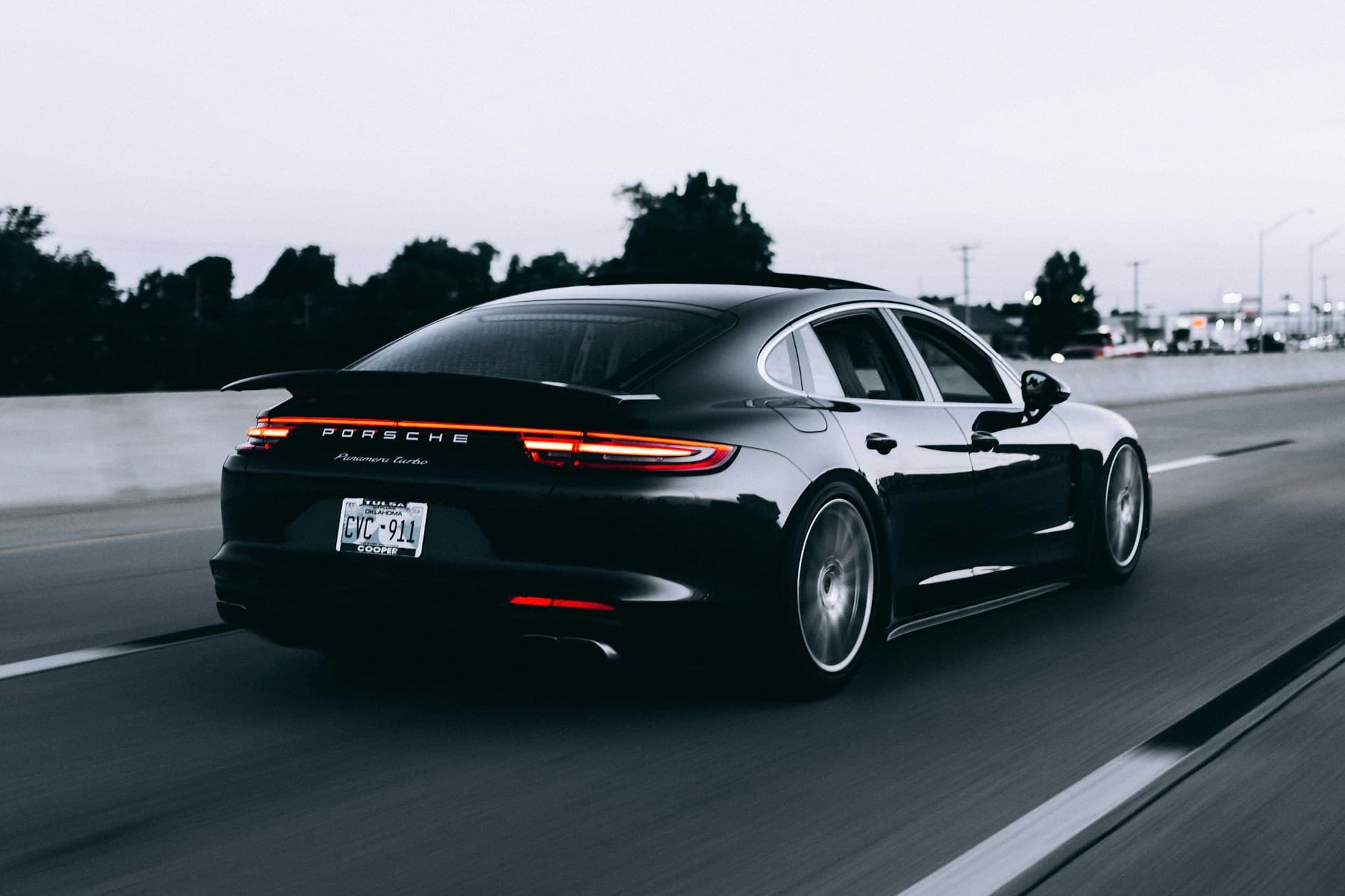 A dark grey performance car on a tree-lined road — an editorial illustration